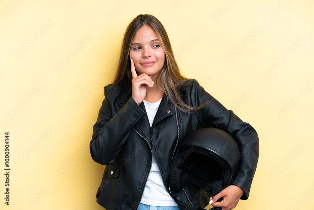Young caucasian woman with a motorcycle helmet isolated on yellow background thinking an idea while looking up Young caucasian woman with a motorcycle helmet isolated on yellow background thinking an idea while looking up