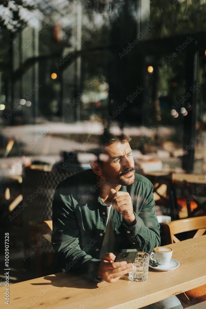 Toughtful man savoring coffee alone at a cozy cafe on a sunny day while lost in contemplation by the window Toughtful man savoring coffee alone at a cozy cafe on a sunny day while lost in contemplation by the window