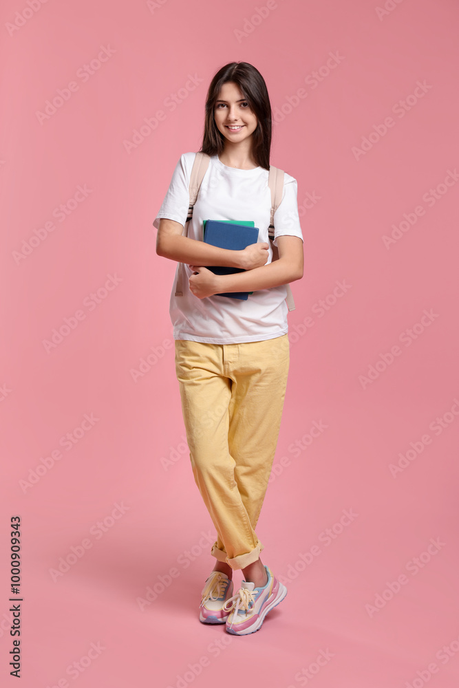 Cute teenage girl with backpack and books on pink background Cute teenage girl with backpack and books on pink background