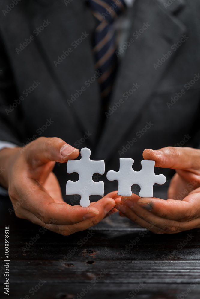 Businessman’s hands hold white jigsaw puzzle piece, symbolizing strategy and problem-solving.importance of teamwork, collaboration, and finding solutions in business challenges and partnerships. Businessman’s hands hold white jigsaw puzzle piece, symbolizing strategy and problem-solving.importance of teamwork, collaboration, and finding solutions in business challenges and partnerships.
