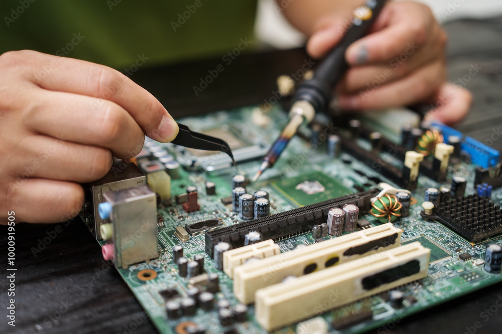 Technician carefully repairs a computer circuit board, using precision tools to address hardware issues. technical expertise needed for troubleshooting and upgrading electronic systems in workspace.