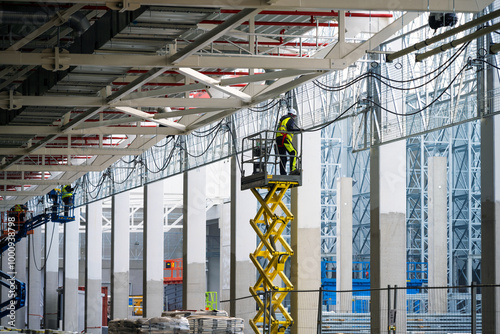 Electricians installing cables on cable trays working at height on construction site