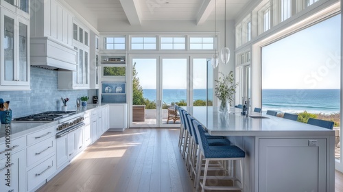 A sleek coastal retreat kitchen, with white cabinetry, blue accents, and large windows framing views of the ocean