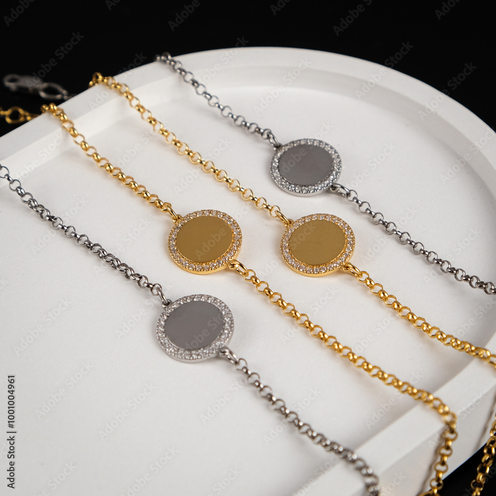 Jewelry for women. Gold and silver bracelets with a pendant on a black background. White stand for jewelry. Jewelry for women. Gold and silver bracelets with a pendant on a black background. White stand for jewelry.