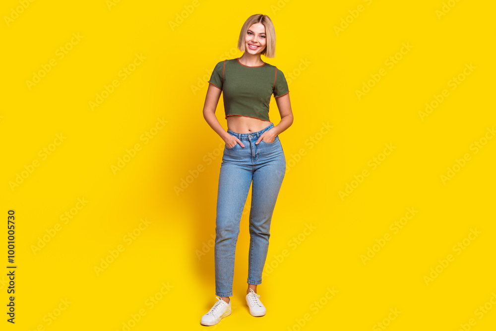 Full length photo of adorable pretty girl dressed khaki t-shirt jeans holding palms in pockets isolated on yellow color background Full length photo of adorable pretty girl dressed khaki t-shirt jeans holding palms in pockets isolated on yellow color background
