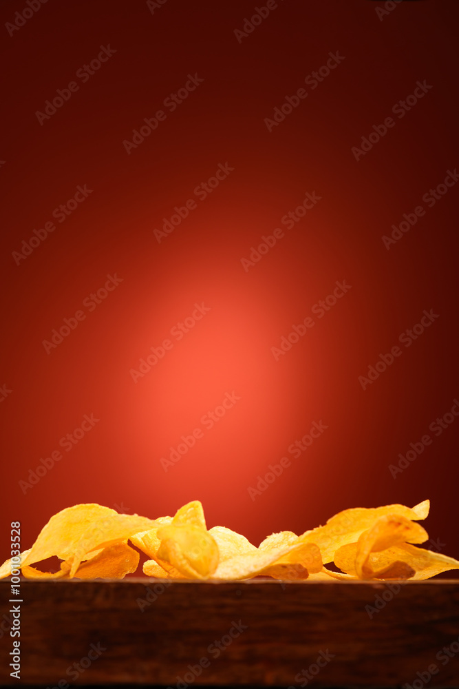 potato chips in a pile on a wooden board on a red background with an empty space potato chips in a pile on a wooden board on a red background with an empty space