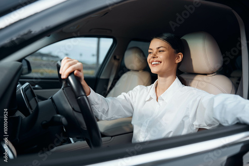 Smiling woman sitting in car driver's seat, hand on steering wheel, looking forward confidently