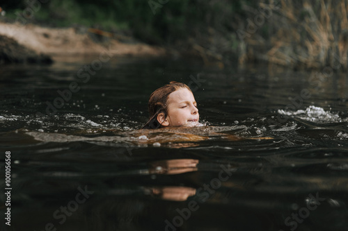 Little girl, child swims in water of lake, sea. Photo, portrait.