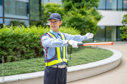 誘導棒を持って交通誘導をするガードマン男性