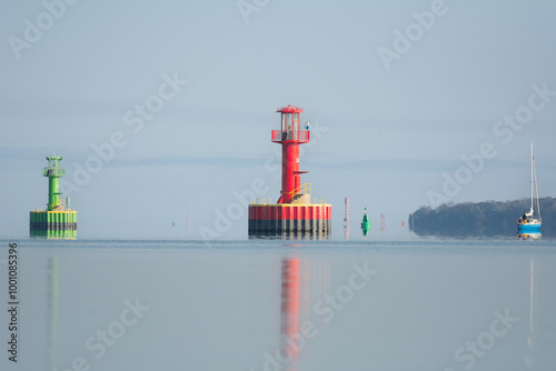 Lighthouse, navigation signs, buoyages, Buoys on calm blue water under blue sky. Photo from Szczecin Lagoon in Poland.