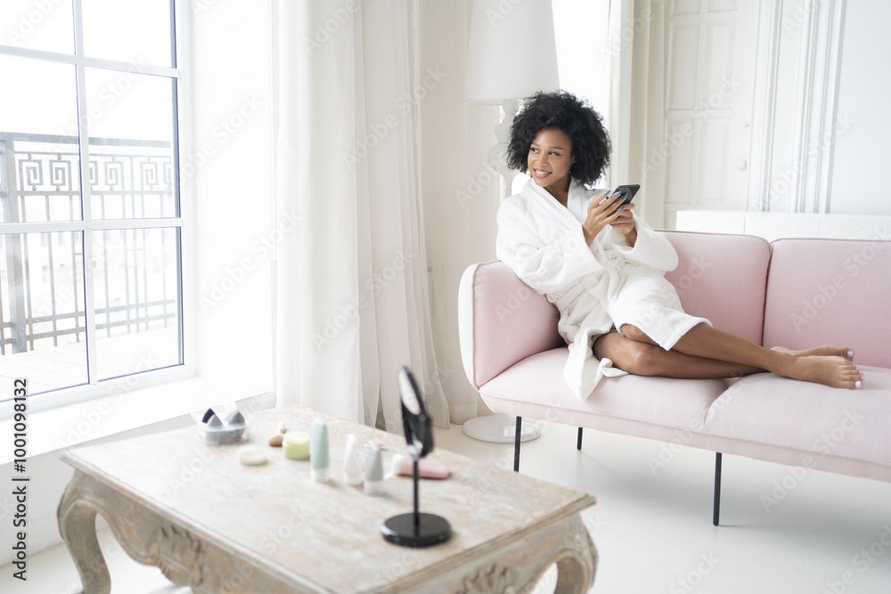 A Relaxed Moment at Home in a Bright Living Room With a Woman in a Robe Enjoying Her Smartphone and Natural Light A Relaxed Moment at Home in a Bright Living Room With a Woman in a Robe Enjoying Her Smartphone and Natural Light
