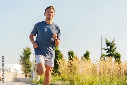 A Man Jogging on a Clear Sunny Day Along a Path Bordered by Tall Grass and Trees in a Peaceful Outdoor Park