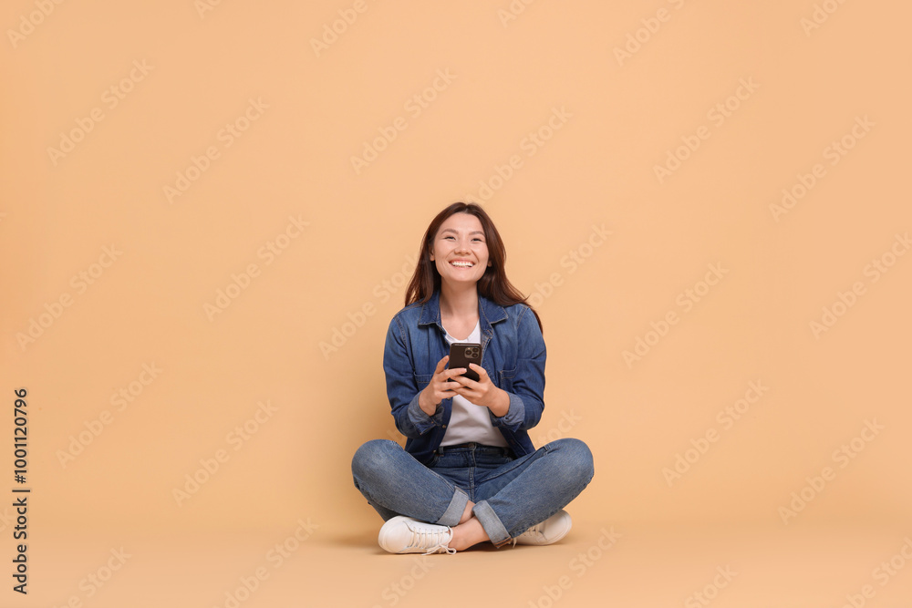 Smiling woman with smartphone on beige background Smiling woman with smartphone on beige background