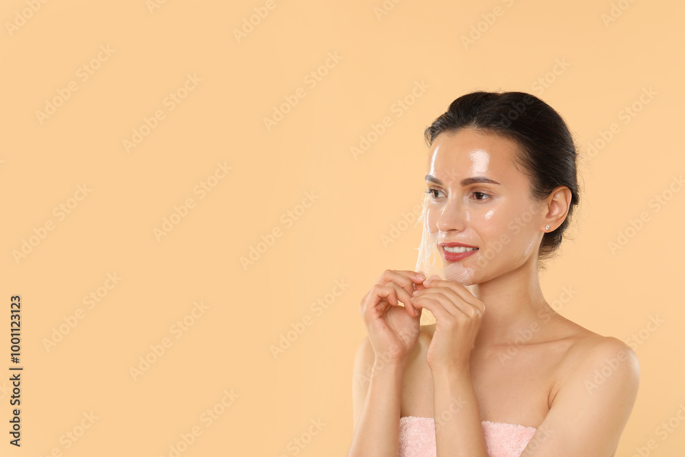 Beautiful woman peeling off face mask on beige background. Space for text Beautiful woman peeling off face mask on beige background. Space for text