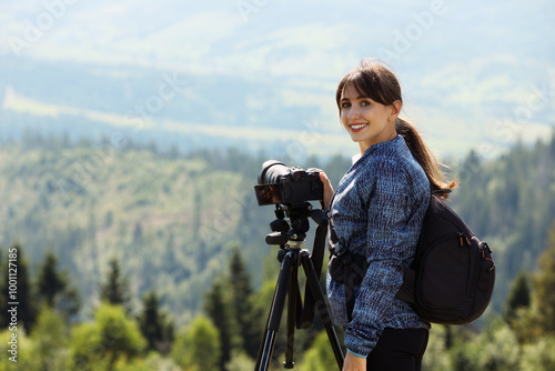 Photographer with backpack and camera on tripod taking picture of beautiful mountains. Space for text