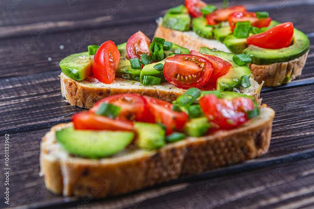 Avocado toast topped with tomato and green onion on a slice of carrot bread Avocado toast topped with tomato and green onion on a slice of carrot bread