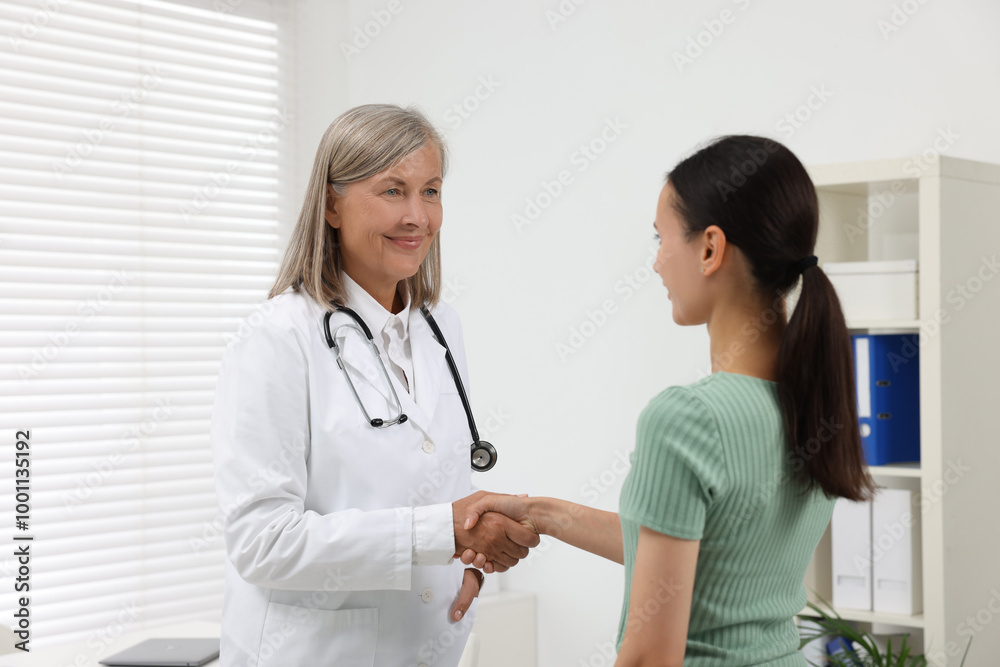 Senior doctor shaking hands with patient in hospital Senior doctor shaking hands with patient in hospital