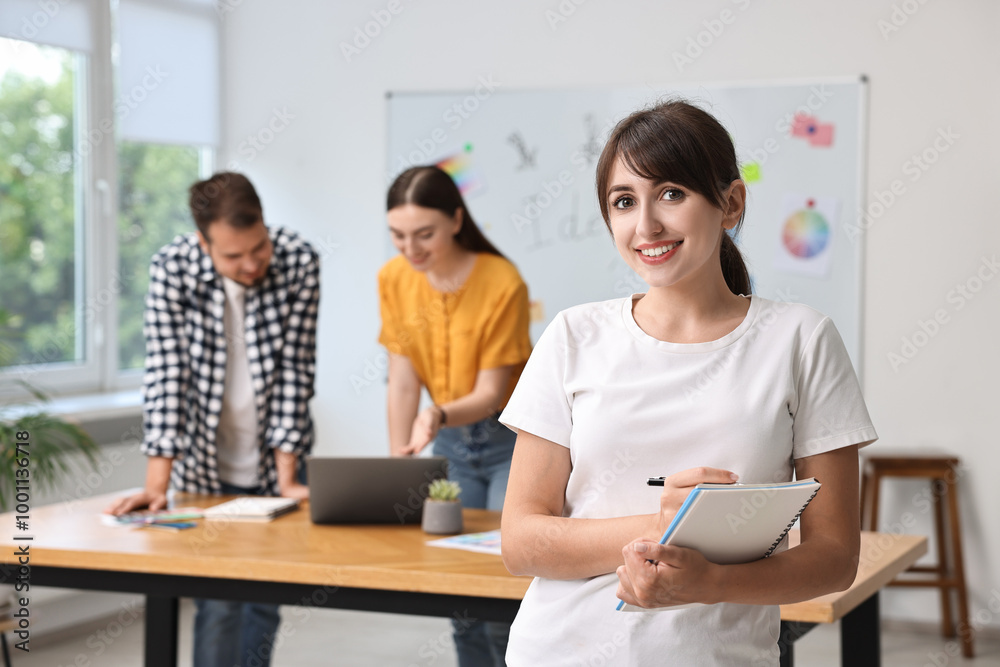 Happy young designer with notebook in office Happy young designer with notebook in office