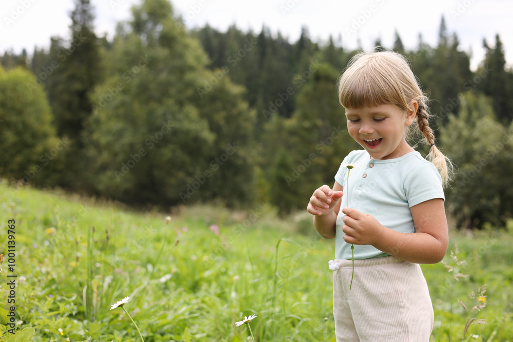 Happy little girl with flower at meadow, space for text. Child enjoying beautiful nature Happy little girl with flower at meadow, space for text. Child enjoying beautiful nature