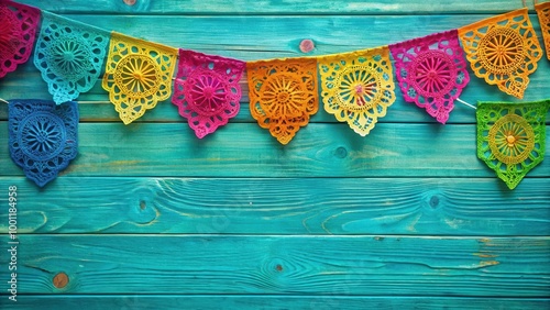 Colorful papel picado banners on teal wooden background for Mexican fiesta celebration