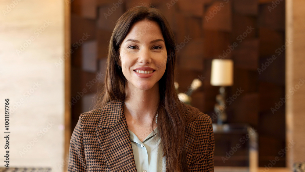 Confident young woman smiles as she stands in the sleek lobby of her company Confident young woman smiles as she stands in the sleek lobby of her company