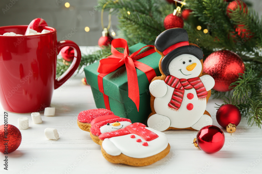 Delicious cookies in shape of snowmen, cup with cocoa and Christmas decor on white wooden table Delicious cookies in shape of snowmen, cup with cocoa and Christmas decor on white wooden table