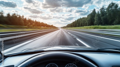 Speeding down an empty highway surrounded by lush forests, the car's dashboard visible in the foreground as sunlight breaks through dramatic clouds above.