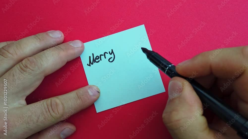 Man writes Merry Christmas note on red background