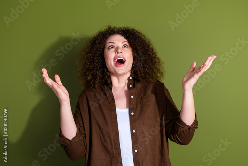 Photo of pretty young woman look up empty space ad wear brown shirt isolated on khaki color background