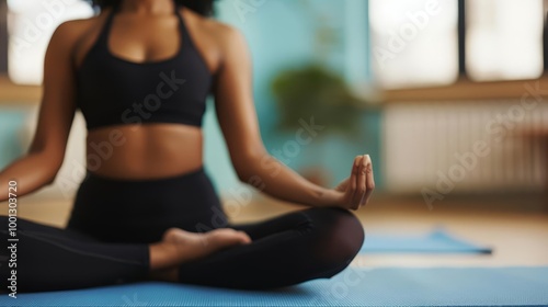 Woman meditating in lotus pose on yoga mat.