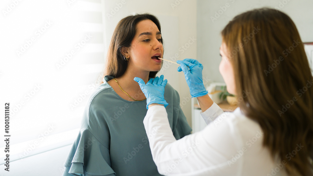 Woman doctor wearing blue gloves performs a throat swab on a patient during a clinic check-up, demonstrating the importance of thorough medical examinations Woman doctor wearing blue gloves performs a throat swab on a patient during a clinic check-up, demonstrating the importance of thorough medical examinations