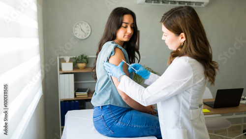 Fotografía Medical professional wearing gloves administers a vaccine to a young woman in a
