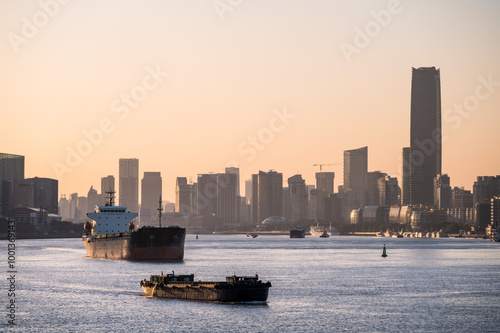 Ships on the Huangpu River and the city skyline in Shanghai at dusk. photo