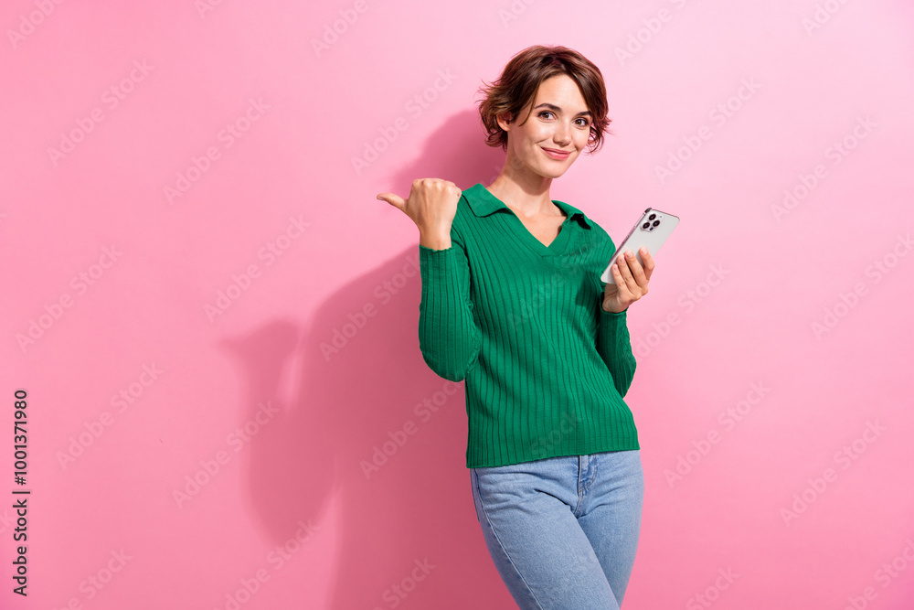 Photo of clever cheerful girl dressed green shirt hold smartphone indicating at offer empty space isolated on pink color background
