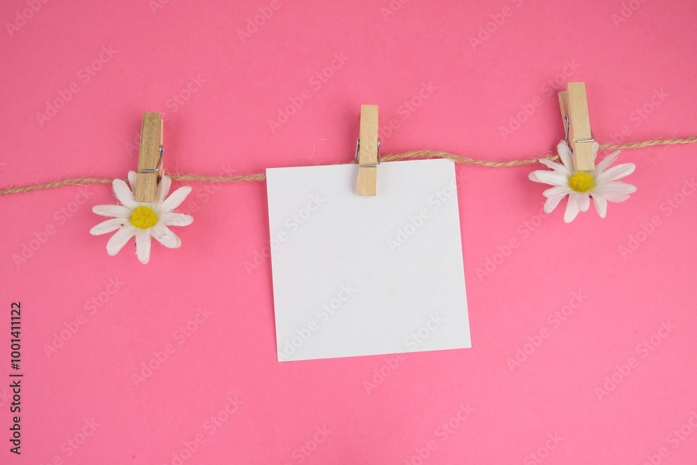 blank paper hanged with flowers on plain background as a memo concept blank paper hanged with flowers on plain background as a memo concept