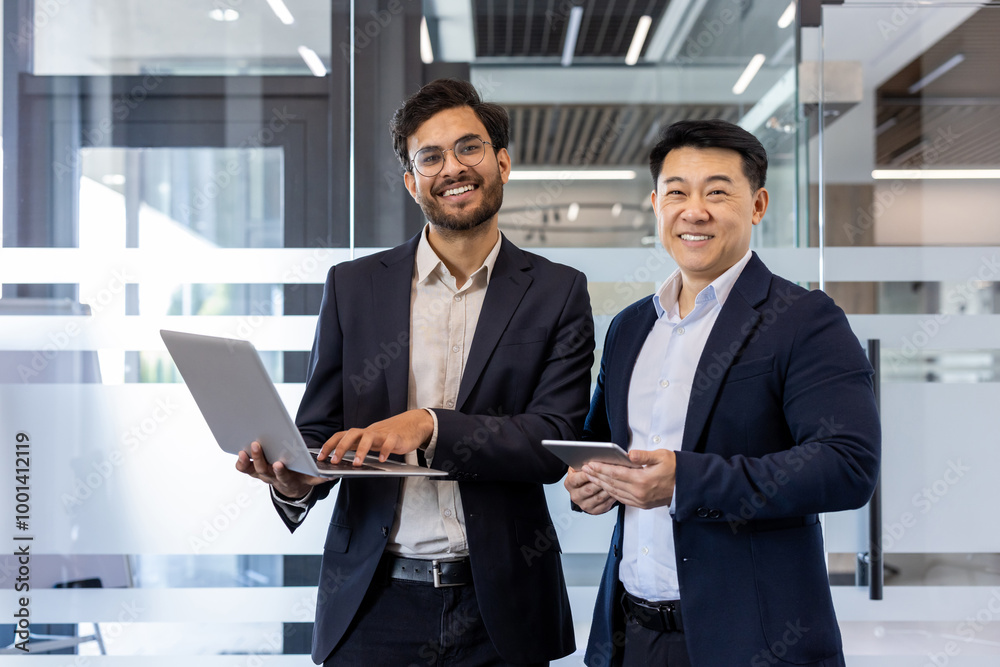 Two confident professionals engage in business discussion using laptop and phone in modern office. Smiling colleagues demonstrate teamwork, collaboration, and effective communication Two confident professionals engage in business discussion using laptop and phone in modern office. Smiling colleagues demonstrate teamwork, collaboration, and effective communication