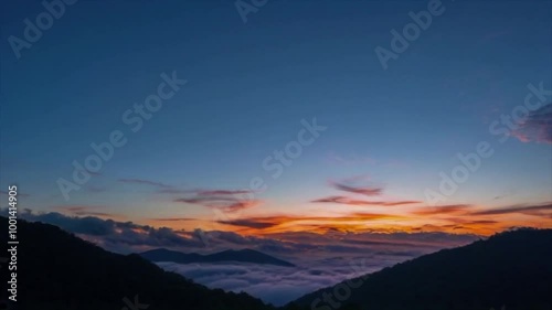 Sunrise emerging from behind mist-covered mountains. dramatic mountain landscapes timelapse