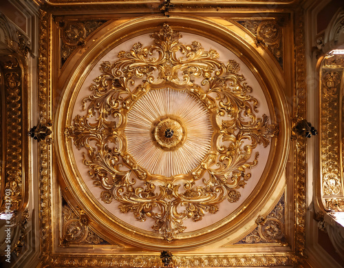  golden Baroque ceiling medallion with intricate scrollwork and ornate floral designs, placed in the center of a grand ballroom, bathed in soft chandelier light