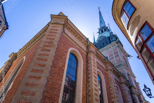 Imposing red brick facade with Gothic spire against blue sky. Architectural detail, historic landmark, Stockholm, Sweden. photo