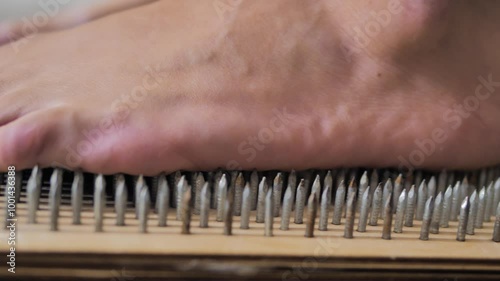 Close-up of a man's foot becoming on nails, helped by hands. Nailing. Practice.