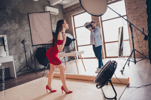 Photo of professional cameraman recording video of passionate seductive woman dressed red outfit indoors workplace studio photo