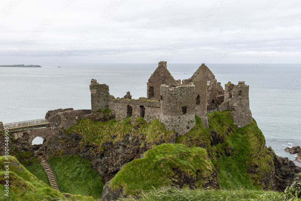 Dunluce Castle sits on a unique rocky cliff overlooking the ocean, with steep green slopes and rugged terrain. This historic landmark is framed by the sea and cloudy sky Dunluce Castle sits on a unique rocky cliff overlooking the ocean, with steep green slopes and rugged terrain. This historic landmark is framed by the sea and cloudy sky