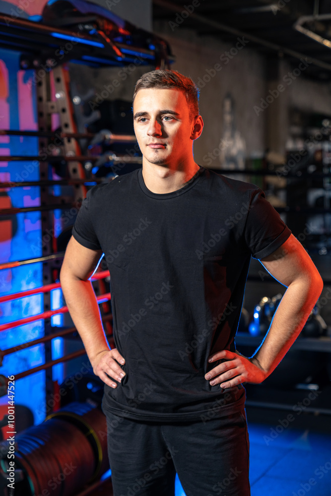 Young man posing confidently in a modern gym. A young man stands confidently with hands on hips in a well-equipped gym, showcasing fitness and a dedicated atmosphere. Young man posing confidently in a modern gym. A young man stands confidently with hands on hips in a well-equipped gym, showcasing fitness and a dedicated atmosphere.