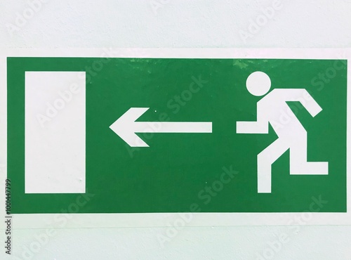 A green exit sign featuring a running man and a left arrow