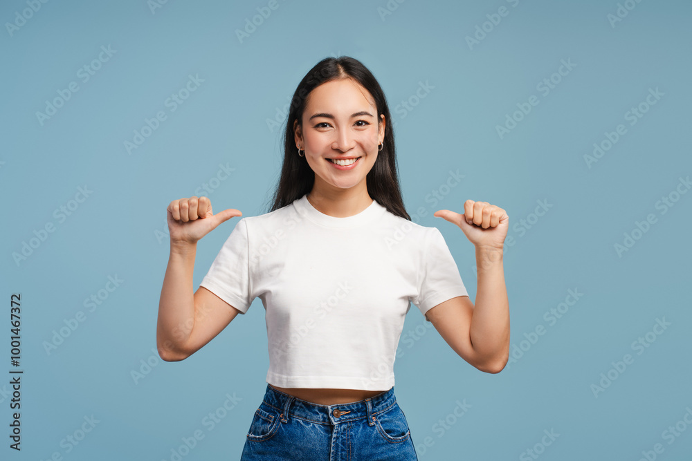 Young, smiling Asian woman pointing thumbs at herself, mockup, copy space Young, smiling Asian woman pointing thumbs at herself, mockup, copy space