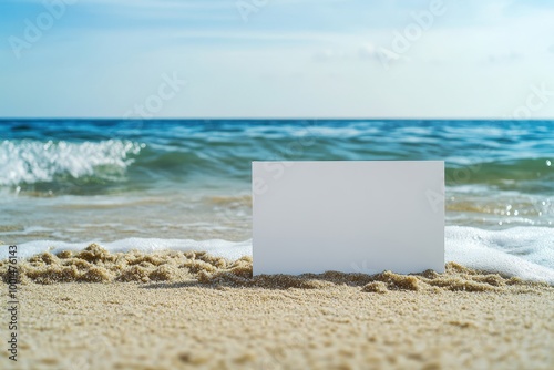 A white card is on the beach with the ocean in the background