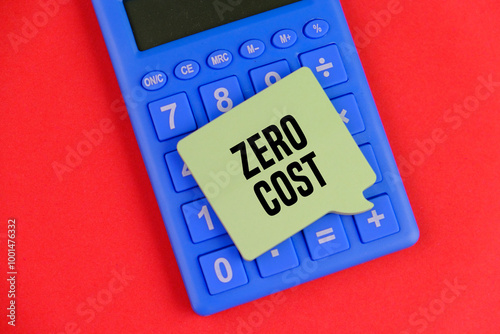 calculator and yellow note pad with text ZERO COST as a financial and business concept on red background. photo