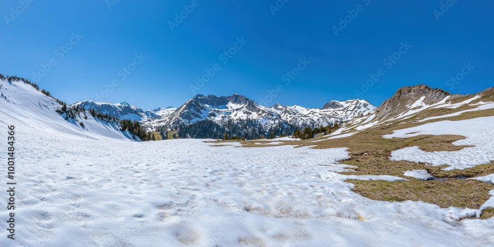 A wide-angle shot of a snowy mountain range under a clear blue sky, with patches of greenery visible on the slopes. A wide-angle shot of a snowy mountain range under a clear blue sky, with patches of greenery visible on the slopes.