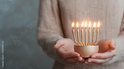 A person holds a lit menorah with seven flames, symbolizing celebration and tradition, against a soft, muted background. photo