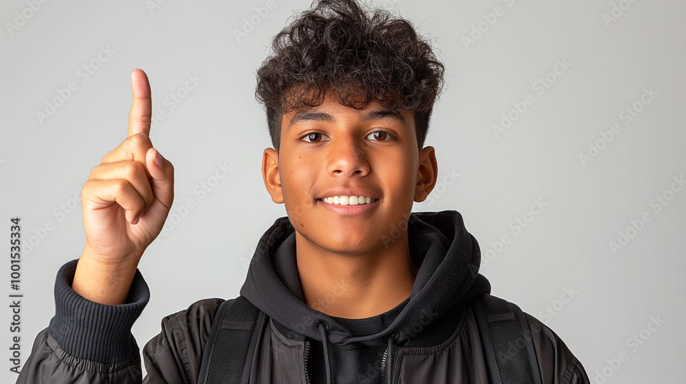 Portrait of a young man smiling with curly hair, wearing a jacket, finger raised in a gesture Portrait of a young man smiling with curly hair, wearing a jacket, finger raised in a gesture